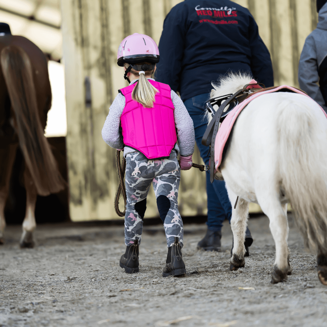 Karupsnäs-Ridakademi-Ridskola Barn med rosa säkerhetsväst leder liten vit ponny